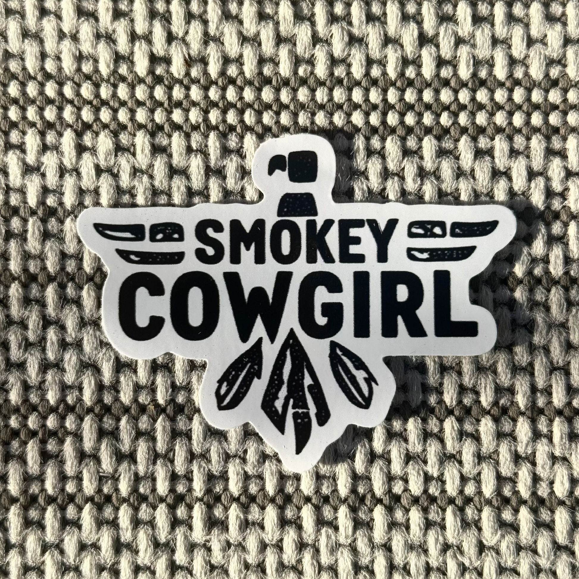 Sticker with 'Smokey Cowgirl' text on a textured fabric background
