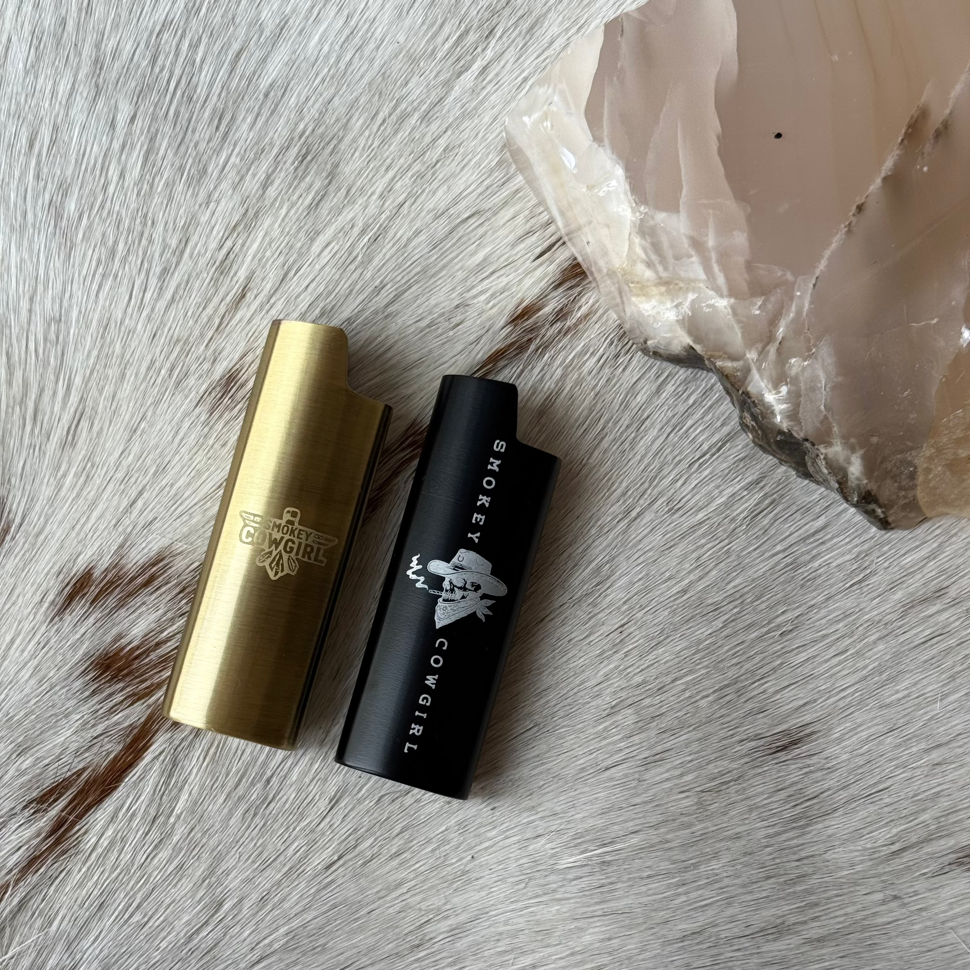 Two lip lighter sleeves, one gold and one black, on a textured surface.