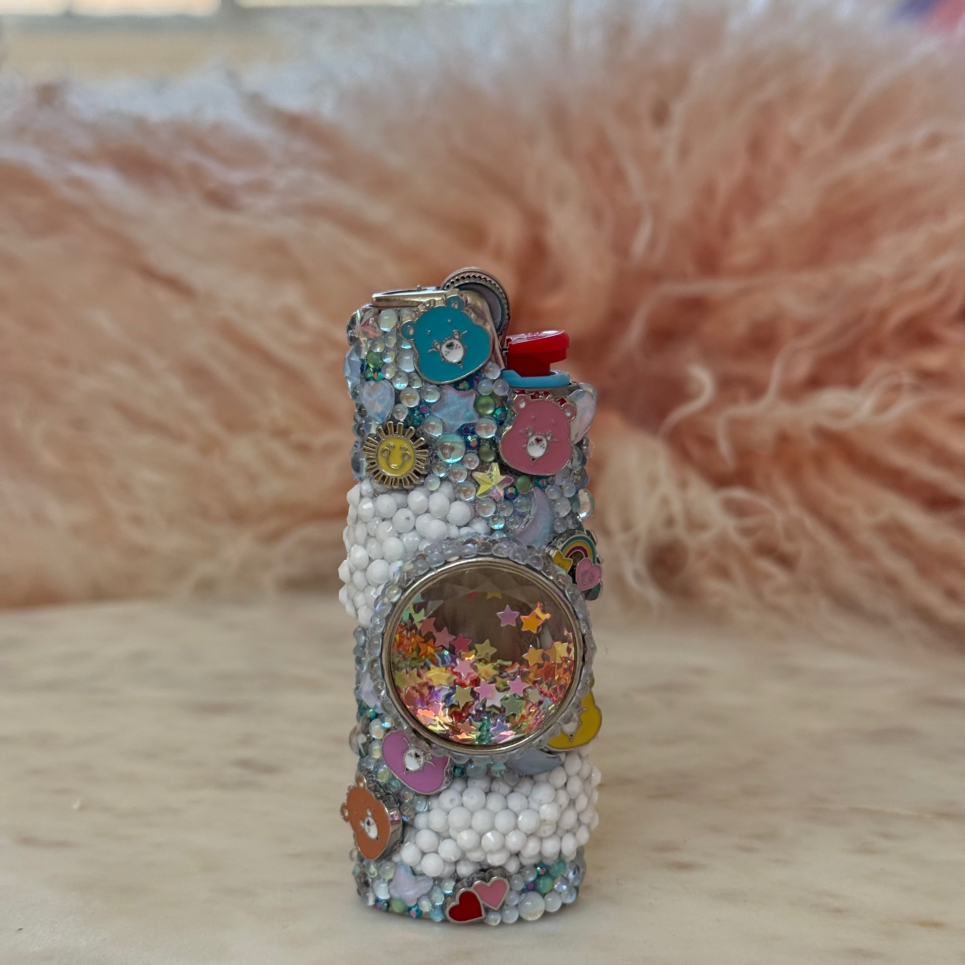 Decorative bottle with colorful embellishments on a wooden surface with a fluffy pink background